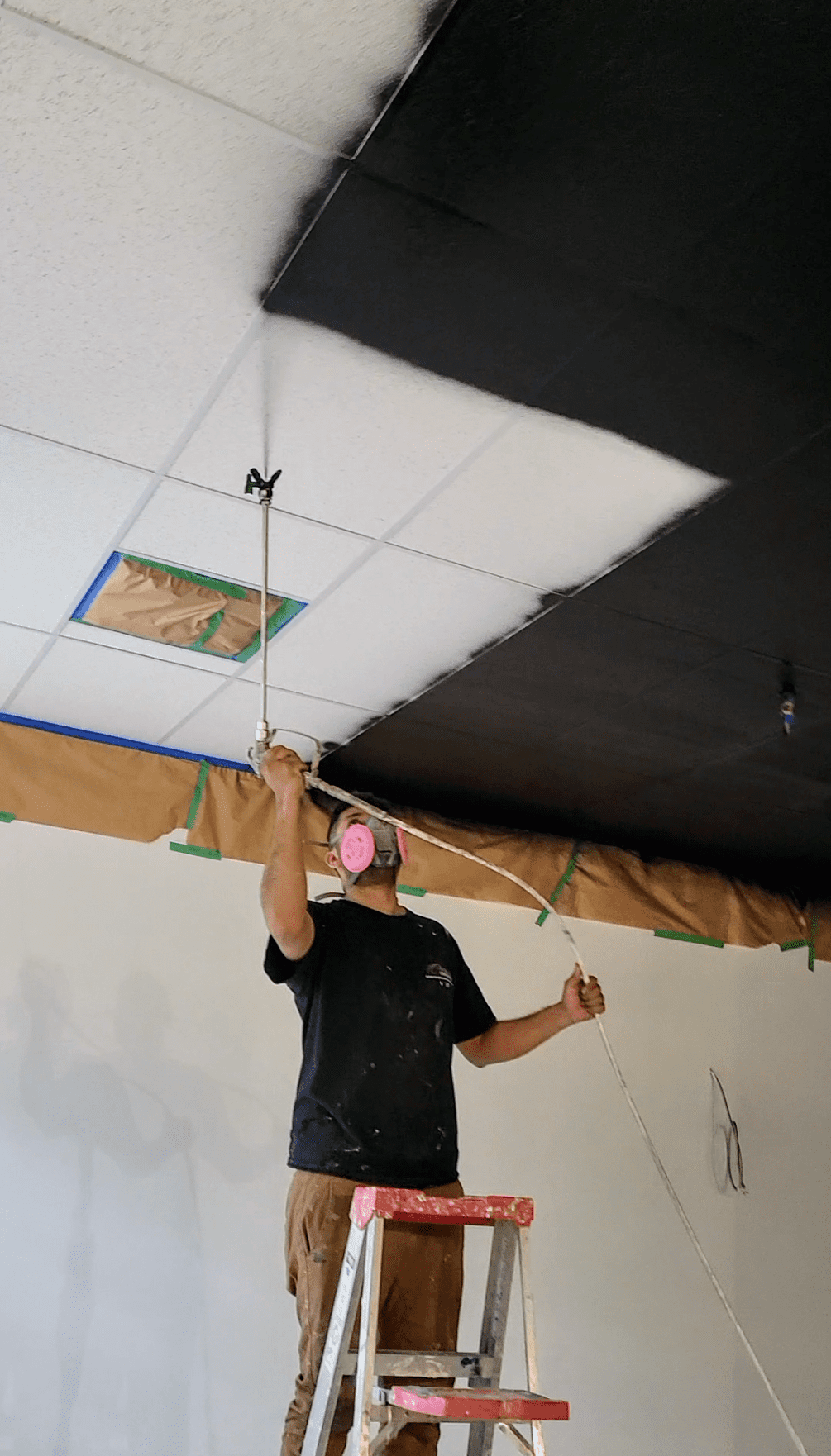 Painter spray painting a drop ceiling