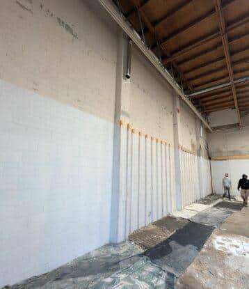 2 employees preparing for interior commercial painting by laying down a bunch of drop sheets to prevent spills.