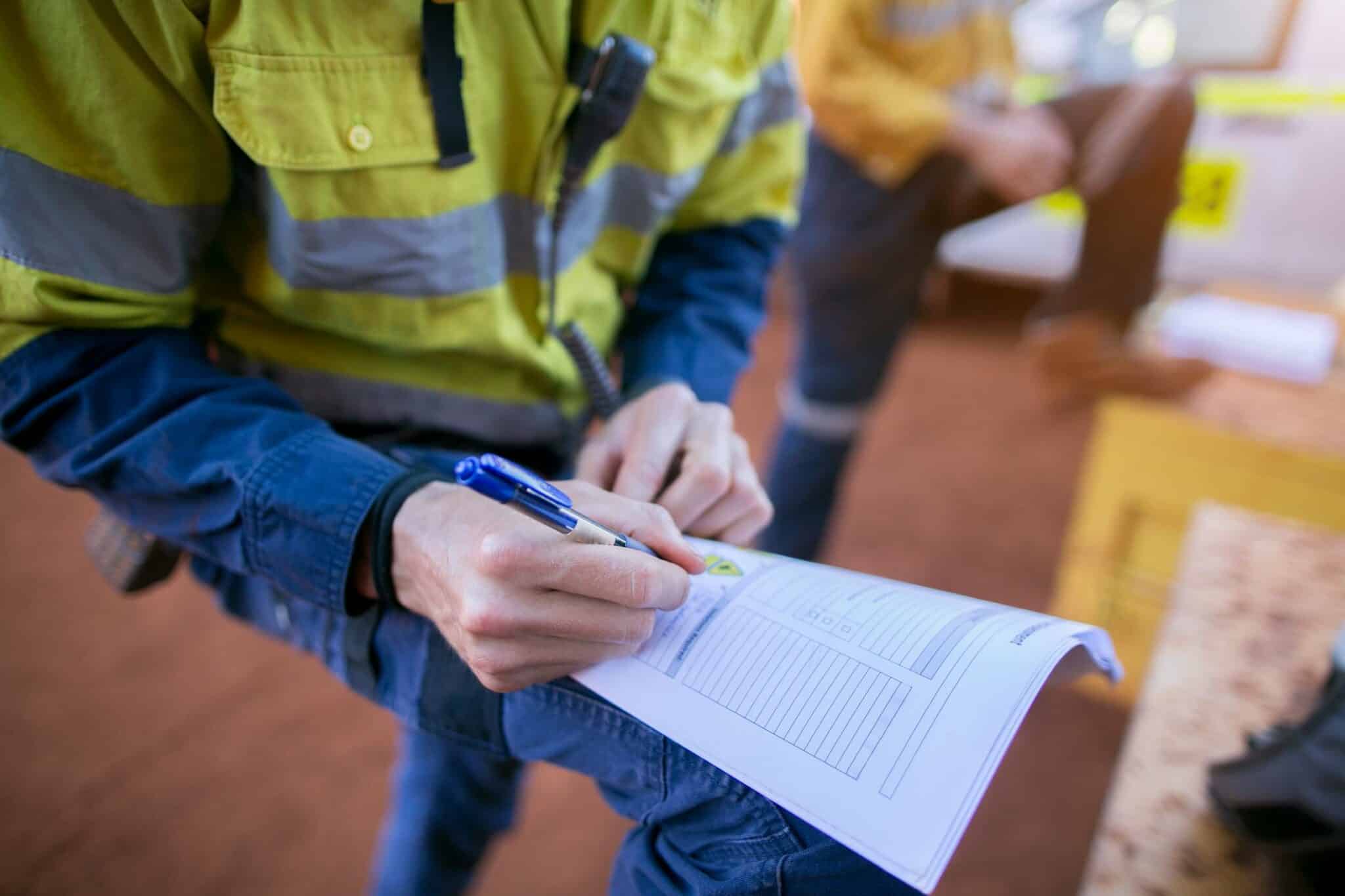 Construction coal miner supervisor conducting safety checking on job hazards analysis on hot work permit before sign off 151914768