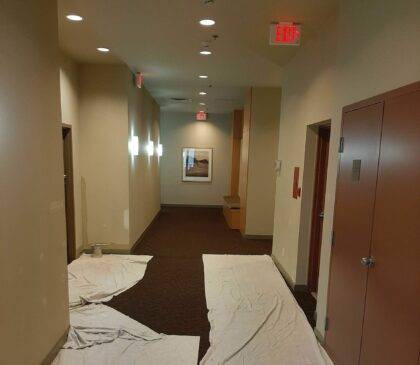 Inside a strata owned property hallways. Drop sheets are laid down on top of a carpet hallway to protect the floor from spills from painting of the walls.