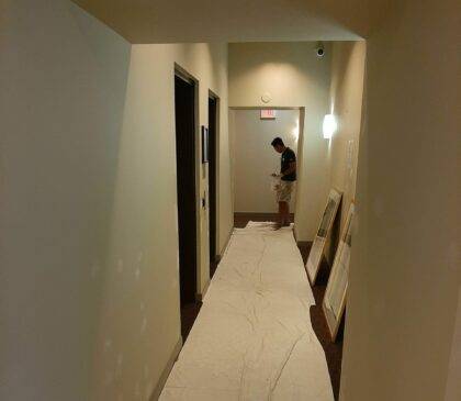 A painter doing drywall repairs and sanding the walls before painting can commence.